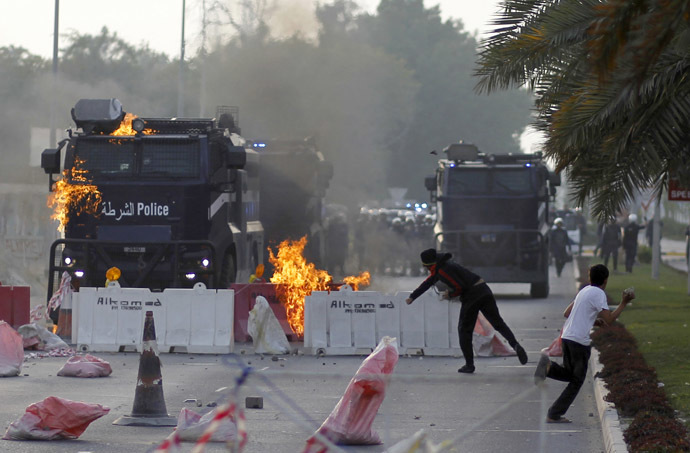 Anti-government protester throws a Molotov cocktail at a riot-police armored personnel carrier during clashes in Diraz