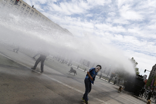 A Mapuche Indian activists dodges a jet of water during a protest against Columbus Day in Santiago