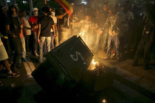 Protesters, whom are mainly Israeli Jews of Ethiopian origin, stand next to a garbage bin they set on fire at Rabin Square during a demonstration against what they say is police racism and brutality, after the emergence last week of a video clip that showed policemen shoving and punching a black soldier at a protest in Tel Aviv May 3, 2015. Israeli mounted police charged hundreds of ethnic Ethiopian citizens and fired stun grenades on Saturday to try to clear one of the most violent protests in memory in the heart of Tel Aviv. REUTERS/Baz Ratner - RTX1BDR5