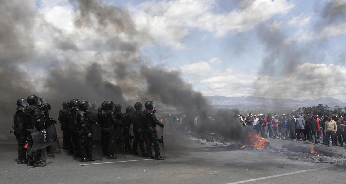 Security forces stand behind a burning road block set up by indigenous protesters from the highlands along the Panamerican Highway during a general strike in the Chasqui area of Ecuador, Thursday, Aug. 13, 2015. A strike by a broad coalition upset with President Rafael Correa virtually paralyzed the capital, provincial cities and stretches of the Panamerican highway. The protesters are indigenous activists, unionists, environmentalists and members of the traditional political opposition. (AP Photo/Dolores Ochoa)