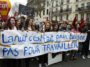 French youths and activists of various youth organisations march with a banner reading 'The night is made for kissing not to work' during a demonstration against proposed changes to labour laws in Paris on March 24, 2016, during a day of action opposing the implementation of new labour legislation. / AFP / DOMINIQUE FAGET