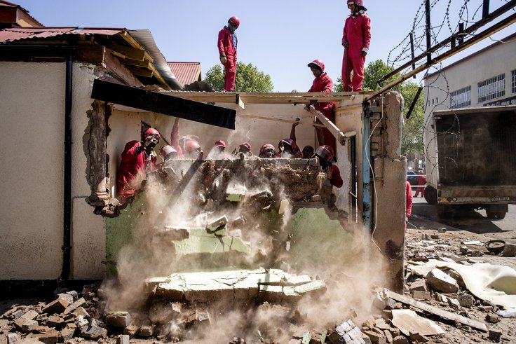 Members of the Red Ants (a local contracted group of workers enforcing municipal orders of demolition or evictions) tear down several structures in central Johannesburg