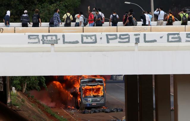 People observe a bus burned by anti-government demonstraters during a protest against the constitutional amendment PEC 55, which limits public spending, in front of Brazil's National Congress in Brasilia, Brazil. REUTERS/Adriano Machado